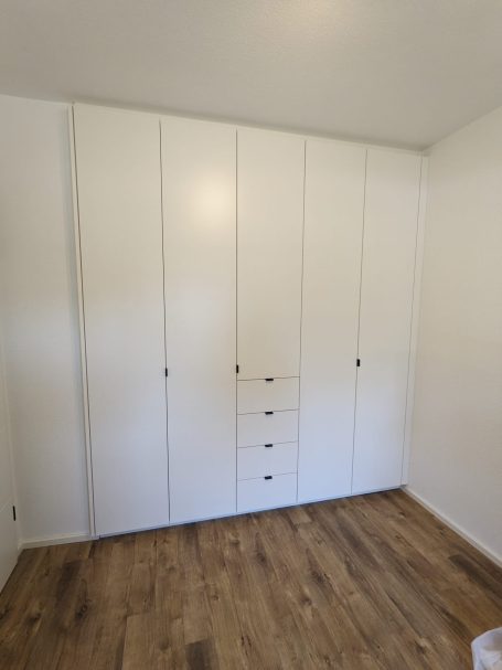 Geschlossener Einbauschrank in Weiß mit schlichten Fronten und integrierten Schubladen.
