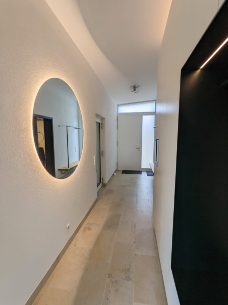 Moderner Eingangsbereich mit Einbauschrank in Weiß mit integrierter schwarzer Sitzfläche und Garderobe.